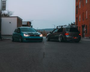 Two Volkswagen cars parked on a city street during twilight, showcasing urban automotive lifestyle.